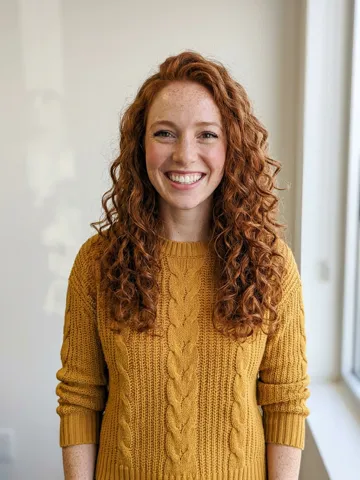 Photo of a red-haired woman in a mustard sweater cast in the spotlight